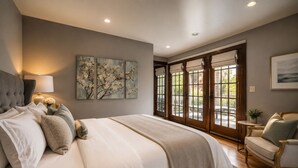 Un dormitorio con una cama grande, una mesita de noche, una lámpara y obras de arte en la pared.