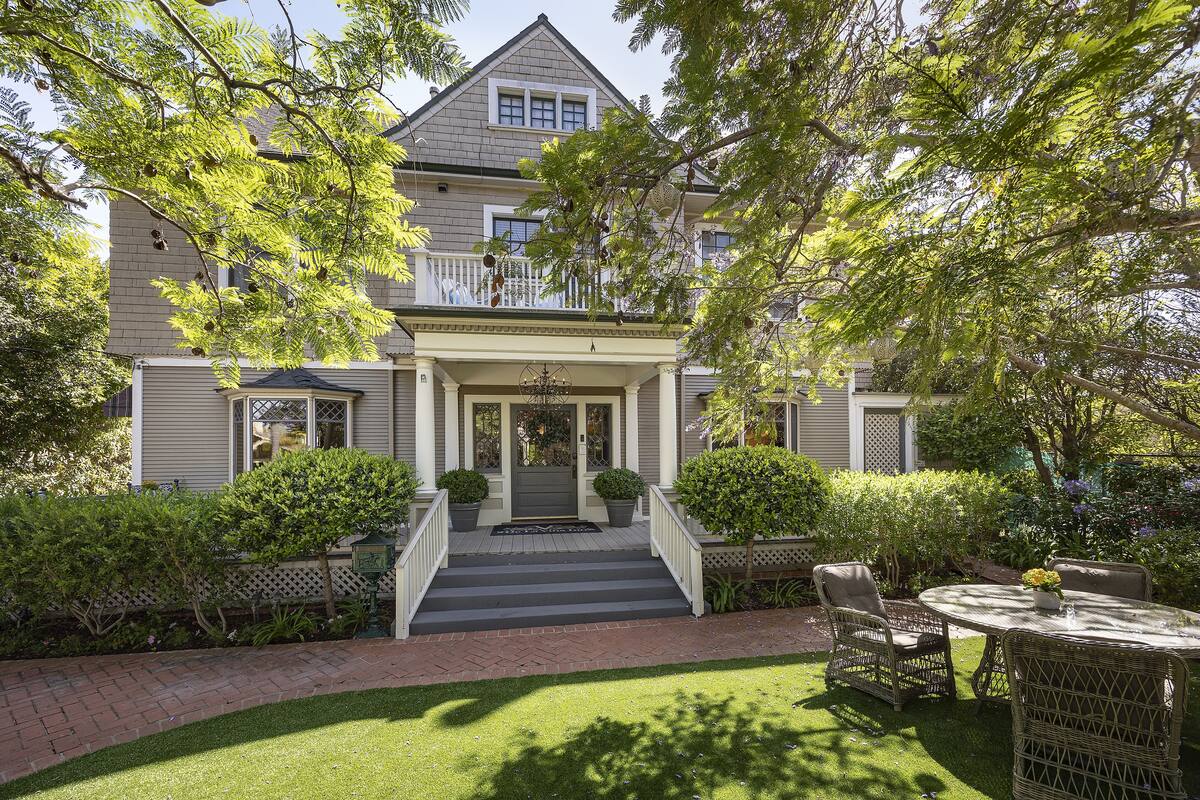 A two-story house with a front porch, a staircase leading to the entrance, and a small patio with outdoor furniture.