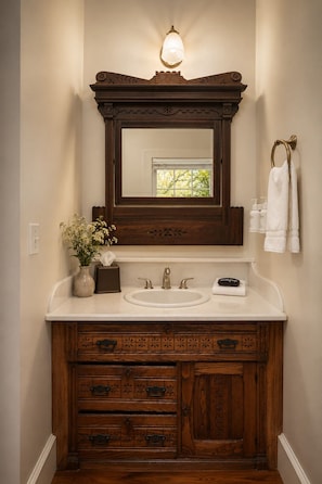 A bathroom with a wooden vanity, a mirror, a sink, and a towel rack. - The De La Vina Inn (Santa Barbara)