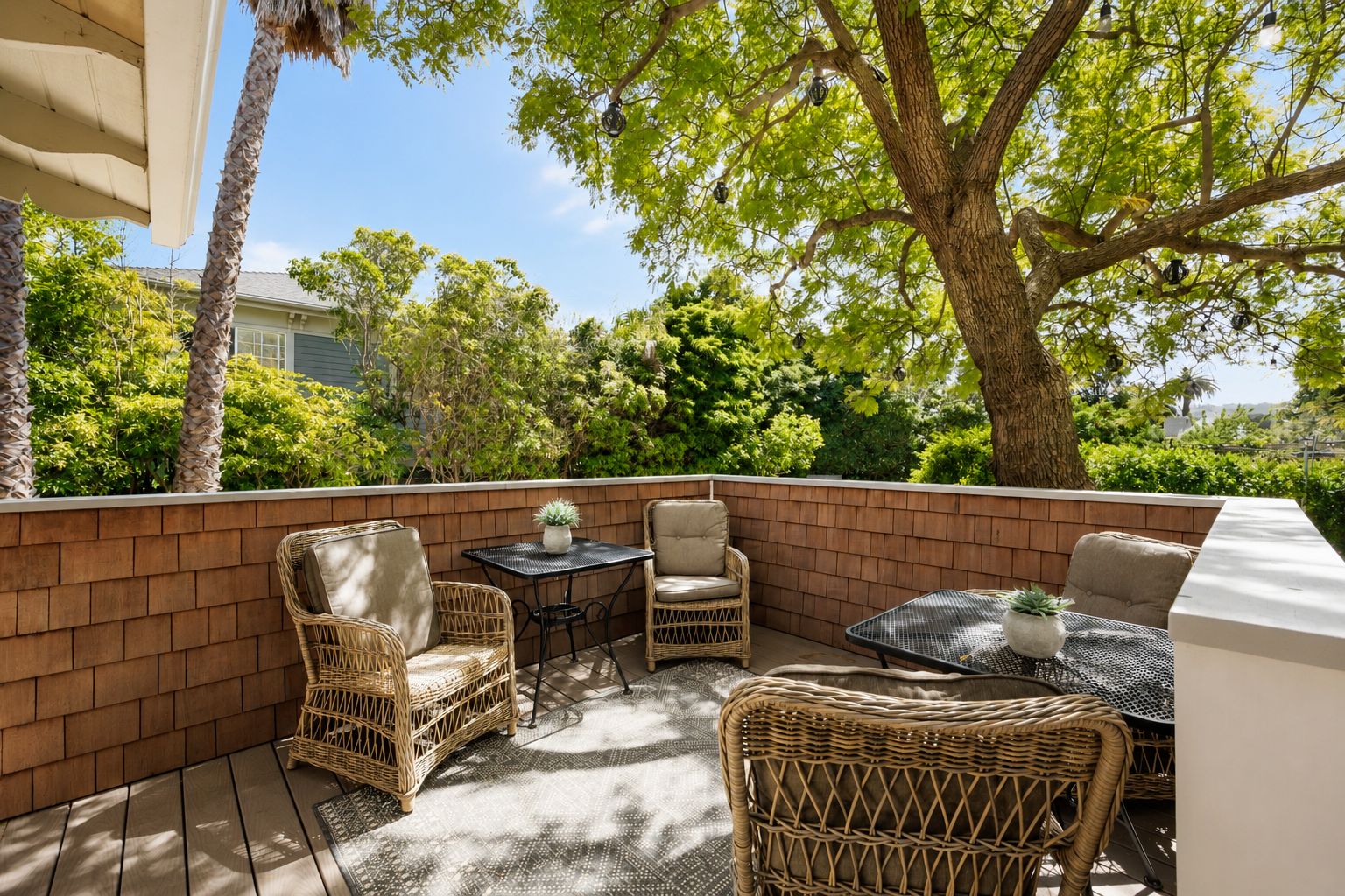 A balcony with wicker furniture, a small table, and a potted plant.