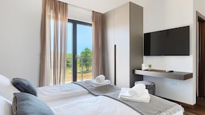 Ein Hotelzimmer mit Bett, Wandfernseher und Blick ins Grüne.