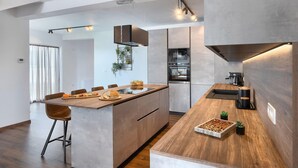 Eine moderne Küche mit einer zentralen Kochinsel, integrierten Geräten und einem Essbereich mit Holztisch und Stühlen.