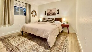 A bedroom with a bed, a ceiling fan, a nightstand with a lamp, and a window with curtains. - 2 Kings • 2 Queens • Fenced Yard • 2 Firepits! (Lakeside)