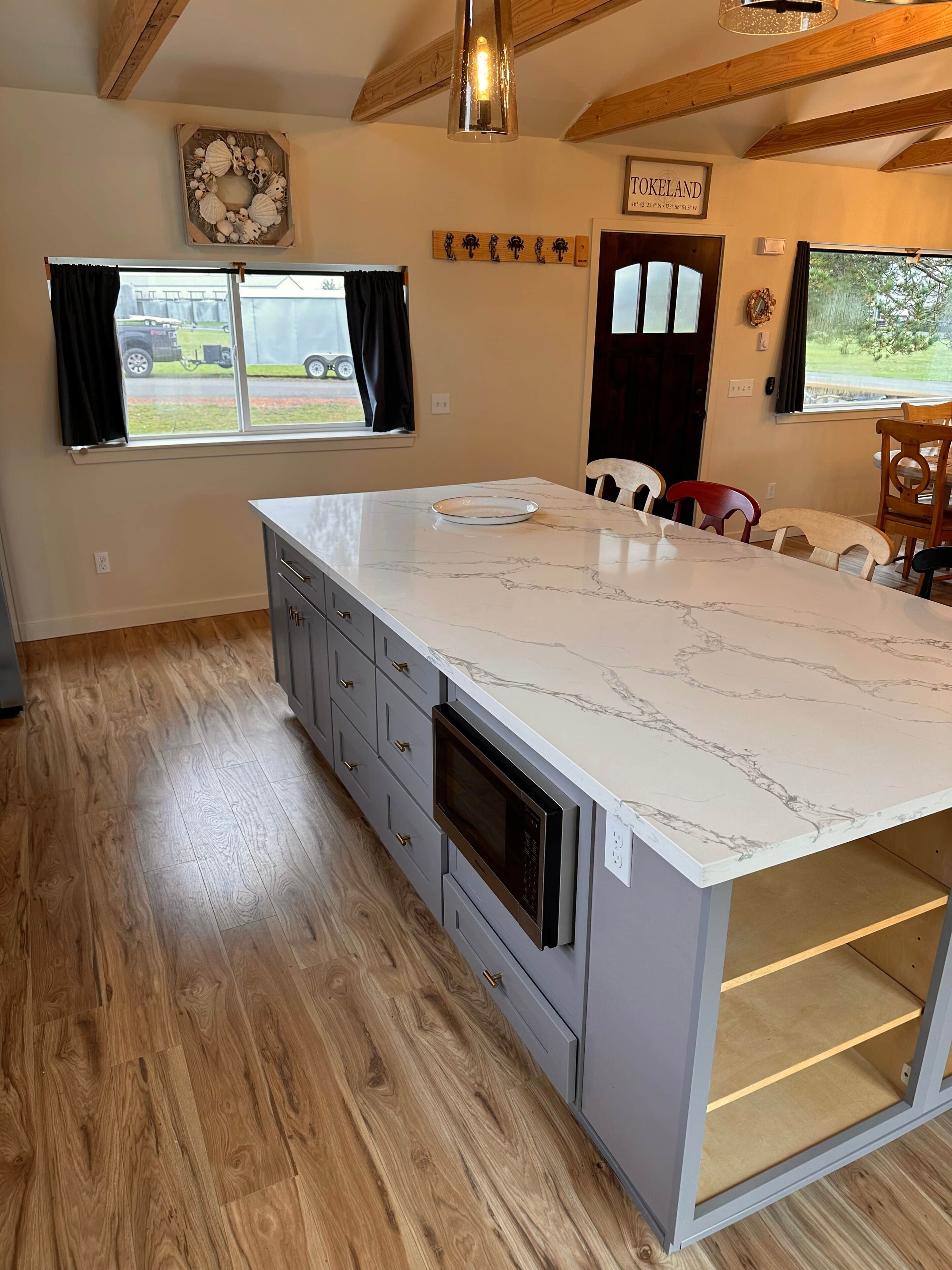 A kitchen with a marble countertop, wooden flooring, and a built-in oven.