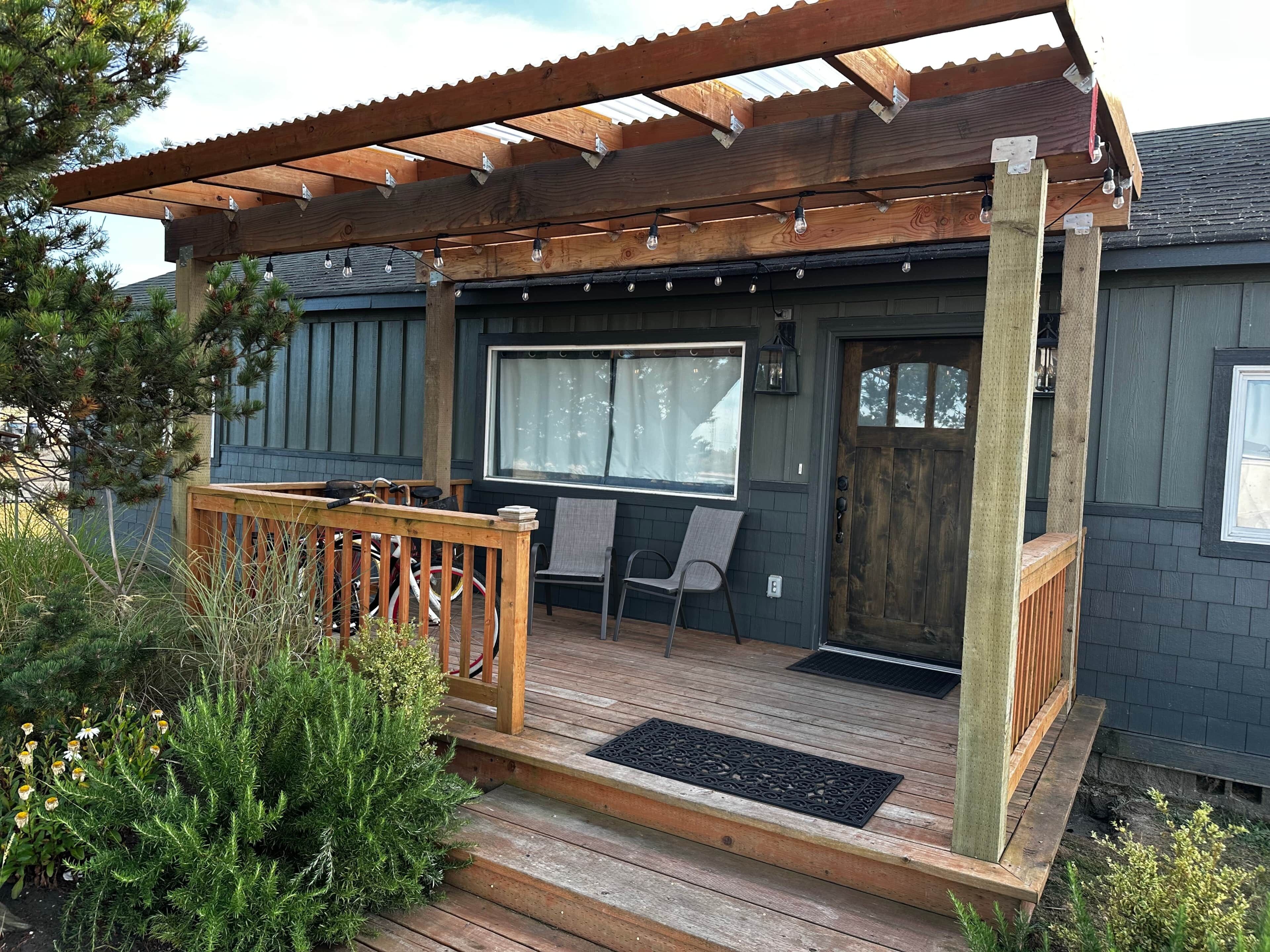 A wooden deck with a pergola, a door, and a window.