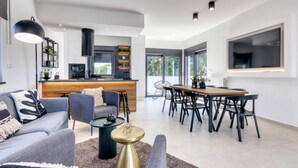 A modern living room with a sofa, coffee table, and dining area with chairs.