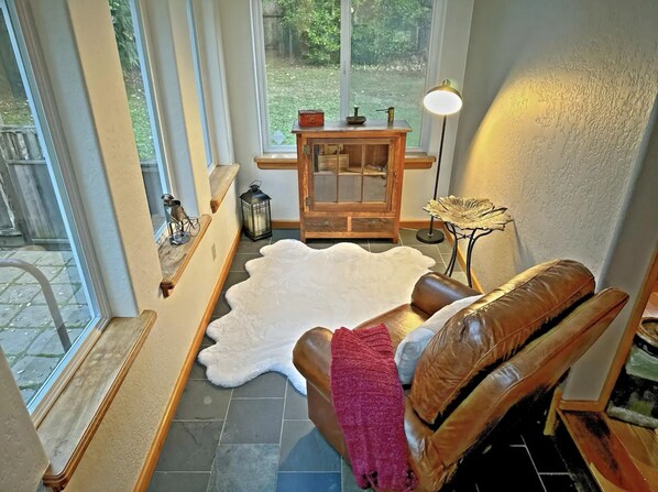 A cozy room with a leather chair, a white fur rug, and a wooden table with a lantern.