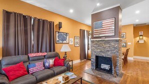 En stue med pejs, en sofa med puder med det amerikanske flag, og en væg med et indrammet amerikansk flag og et kort.