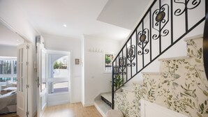 A staircase with ornate metal railings, a white door leading to a room, and a patterned wall.