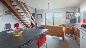 A dining area with a table, chairs, a staircase, and a television. - Villa 'Bellevue Rue De La Petite Corniche' with Sea View, Private Terrace and Wi-Fi (perros guirec)