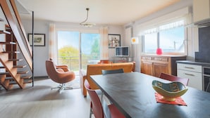 A modern kitchen with a dining area, a TV, and a staircase. - Villa 'Bellevue Rue De La Petite Corniche' with Sea View, Private Terrace and Wi-Fi (perros guirec)