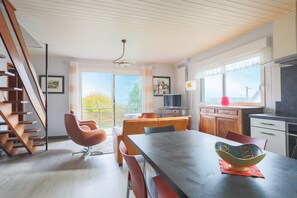 A modern kitchen with a dining area, a TV, and a staircase. - Villa 'Bellevue Rue De La Petite Corniche' with Sea View, Private Terrace and Wi-Fi (perros guirec)