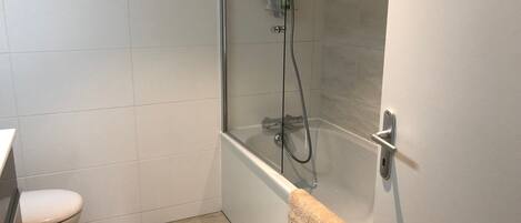 A bathroom with a toilet, a shower with a glass door, and a towel rack.