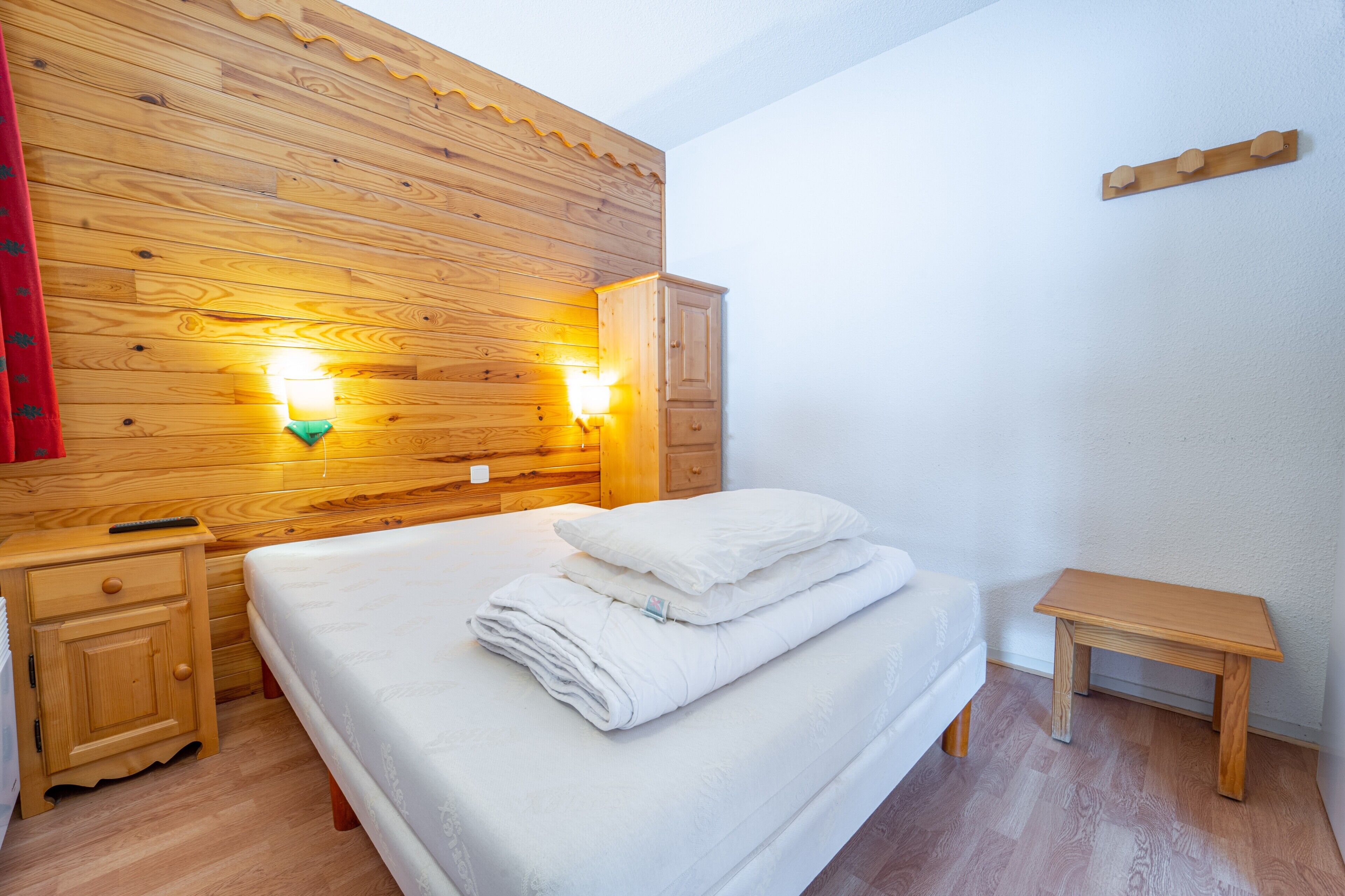 Ein Schlafzimmer mit Holzwänden, einem Bett, Nachttischen und Wandleuchten.