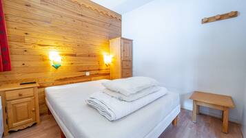 Ein Schlafzimmer mit Holzwänden, einem Bett, Nachttischen und Wandleuchten.