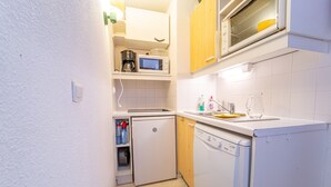 Eine kleine Küche mit Mikrowelle, Kaffeemaschine und Geschirrspüler.