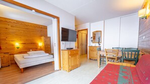 Ein Zimmer mit einem Bett, Holzmöbeln, einem Fernseher und einem roten Teppich mit Muster.