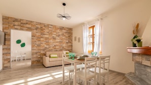 A dining area with a table set for four, a sofa, and a stone wall.