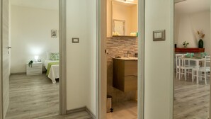 A hotel room with a bed, bedside table, nightstand, and a small window.