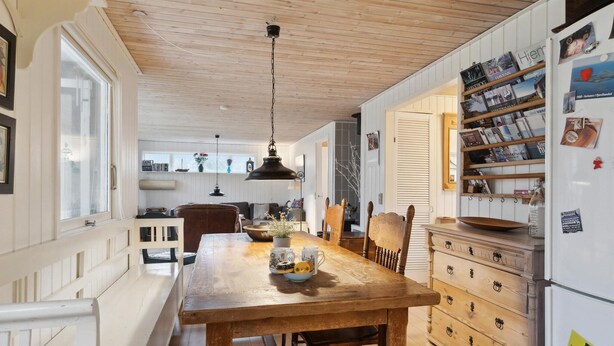 Une cuisine chaleureuse, avec des meubles en bois, un luminaire suspendu et un réfrigérateur orné de divers aimants et de petits mots.