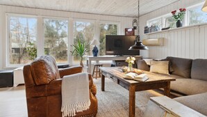 Un salon chaleureux avec un fauteuil en cuir, une table basse en bois, un canapé et un téléviseur.