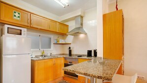 A kitchen with wooden cabinets, a microwave, a stove, and a granite countertop.