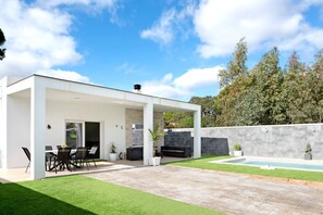 Eine moderne Außenpatio mit Pool, Sitzbereich und überdachtem Bereich.