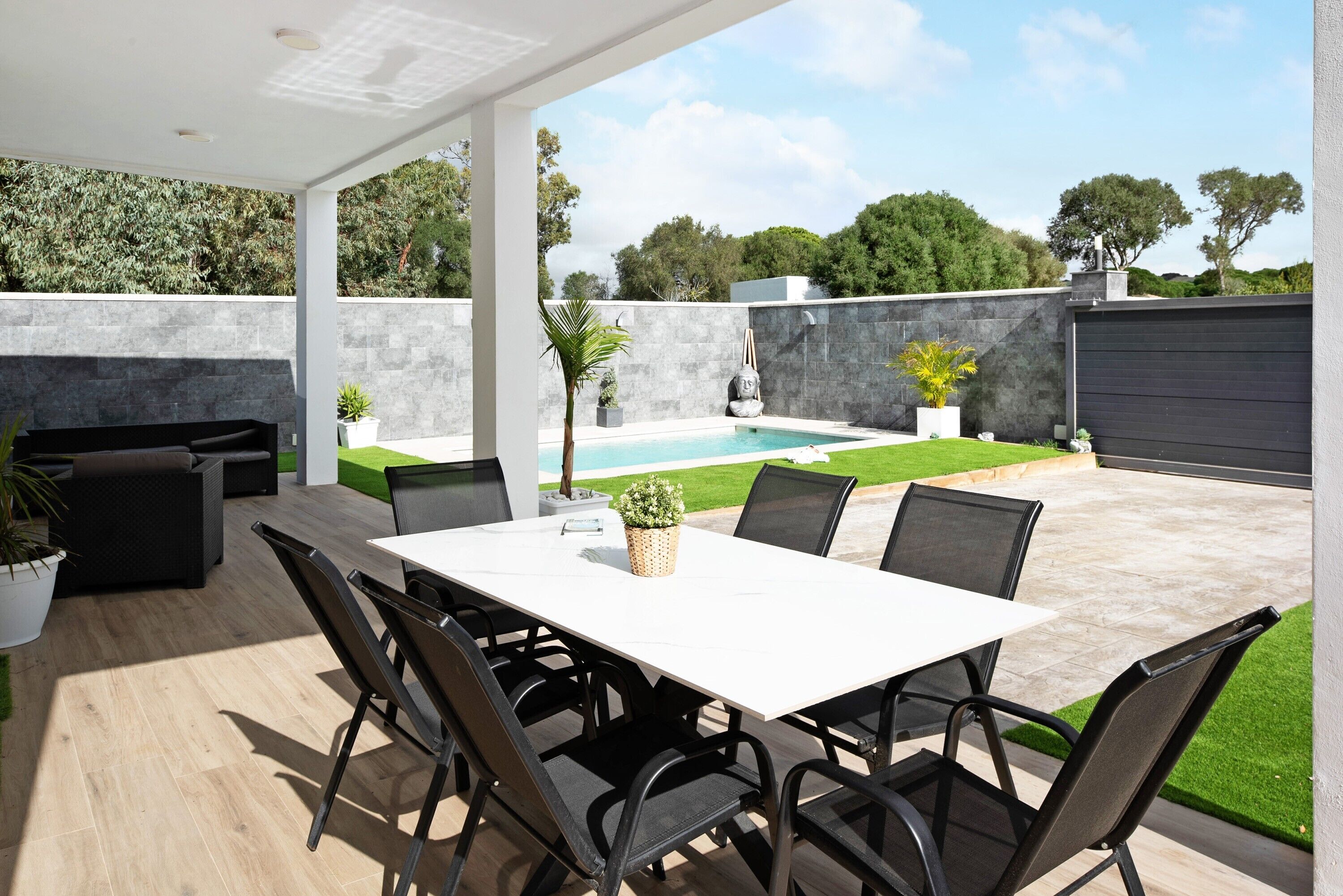 A covered patio area with a pool, outdoor seating, and a table.