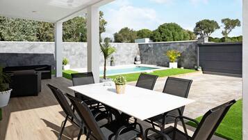 A covered patio area with a pool, outdoor seating, and a table.
