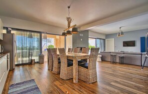 Relax in this open-plan living space with a dining area, sofa, and large sliding door leading to an outdoor area.