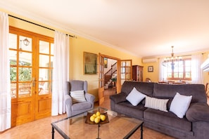 A living room with a sofa, armchair, and a glass coffee table with lemons.