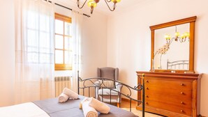 Una habitación de hotel con una cama, una silla, un aparador y un espejo.
