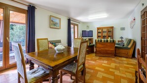Ein Essbereich mit Holztisch und Stühlen, einer Couch, einem Fernseher und einem Schrank.