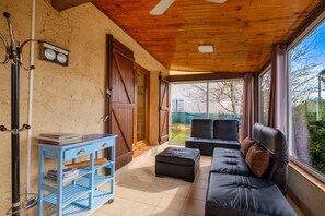 Una habitación con techo de madera, un armario azul, un sofá de cuero negro y un ventanal grande.