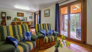 Ein Wohnzimmer mit einer Sofagarnitur, einem Esstisch und Blick durch eine Glastür.