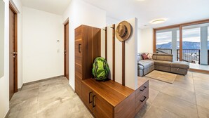 A modern living room with a sofa, a wooden bench, and a hat on the wall. - Apartment 'Klara' with Mountain View, Private Terrace and Wi-Fi (Mölten)
