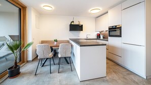A modern kitchen with a central island, white cabinetry, and built-in appliances. - Apartment 'Klara' with Mountain View, Private Terrace and Wi-Fi (Mölten)
