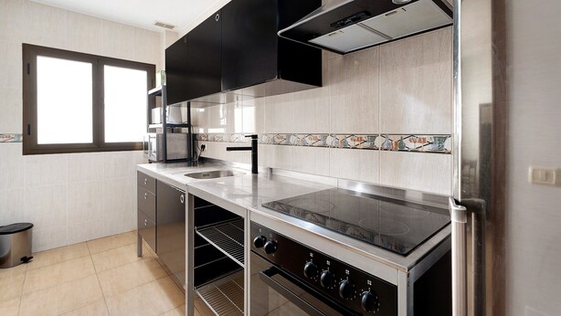 A modern kitchen with stainless steel appliances, a window, and a tiled backsplash. - Apartment 'Noa' with Wi-Fi (San Sebastián de La Gomera)