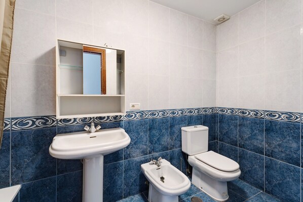 A bathroom with a sink, bidet, toilet, and a mirror above the sink.