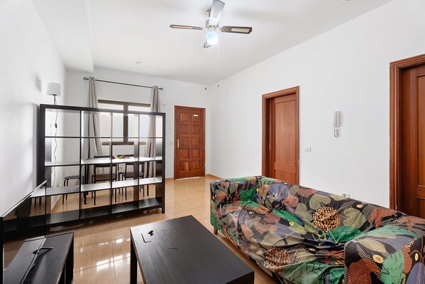 A living room with a sofa, a coffee table, a TV stand, and a ceiling fan. - Apartment 'Noa' with Wi-Fi (San Sebastián de La Gomera)