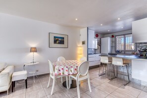 A modern kitchen with white cabinets, a dining area with a table and chairs, and a small bar area.