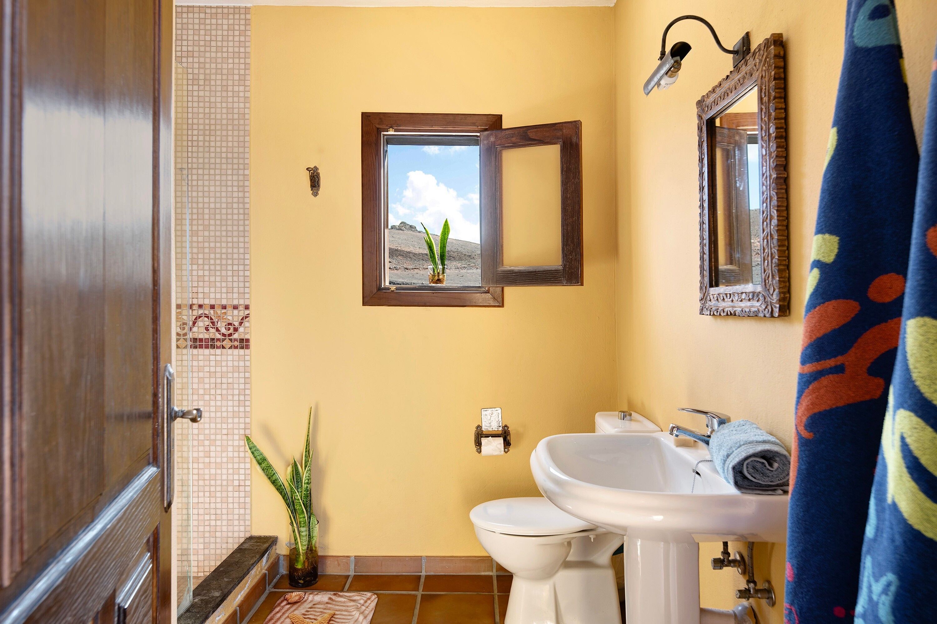 Ein Badezimmer mit Toilette, Waschbecken und einem Fenster mit Blick auf eine Landschaft.