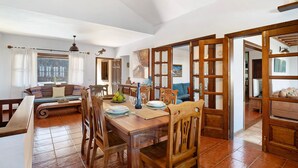 A dining area with a wooden table, chairs, and a large window. - Vacation Home "Finca Acequia" with Sea View, Private Pool & Wi-Fi (Tinajo)