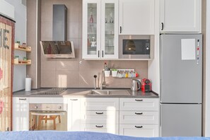Una cocina moderna con muebles blancos, un lavamanos de acero inoxidable, un microondas y un refrigerador.