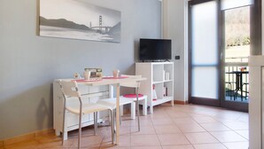 Ein Zimmer mit Esstisch, Stühlen, Fernseher und Bücherregal.