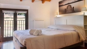 Ein Schlafzimmer mit einem Bett, einem Gemälde, einer Lampe und Blick durch eine Tür.