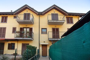 Un bâtiment jaune doté de balcons et d’une porte en bois.