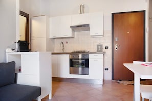 A compact kitchen with white cabinets, a built-in oven, and a stove. - Apartment "Relax tra Monti e Laghi" with Balcony & Wi-Fi (Brenta)