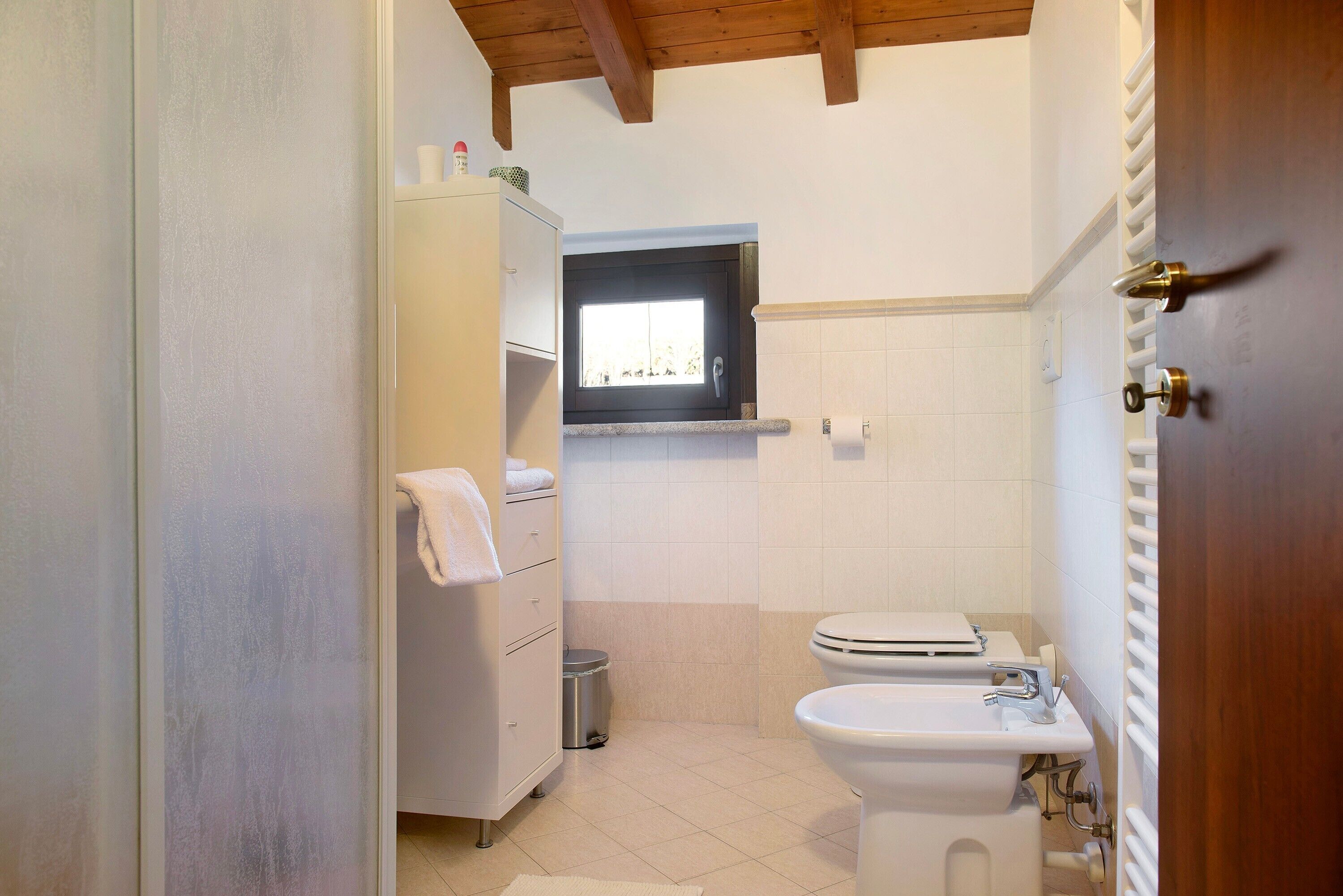 Une salle de bain avec des toilettes, un lavabo et une fenêtre.