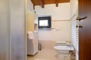 Une salle de bain avec des toilettes, un lavabo et une fenêtre.
